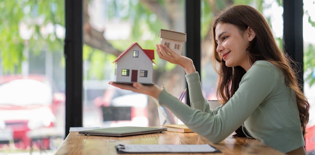 Women support model houses with two hands and give the house over to customers or homebuyers. Rent and buy home or Real Estate Buying Ideas and Investment Banking Finance concept.