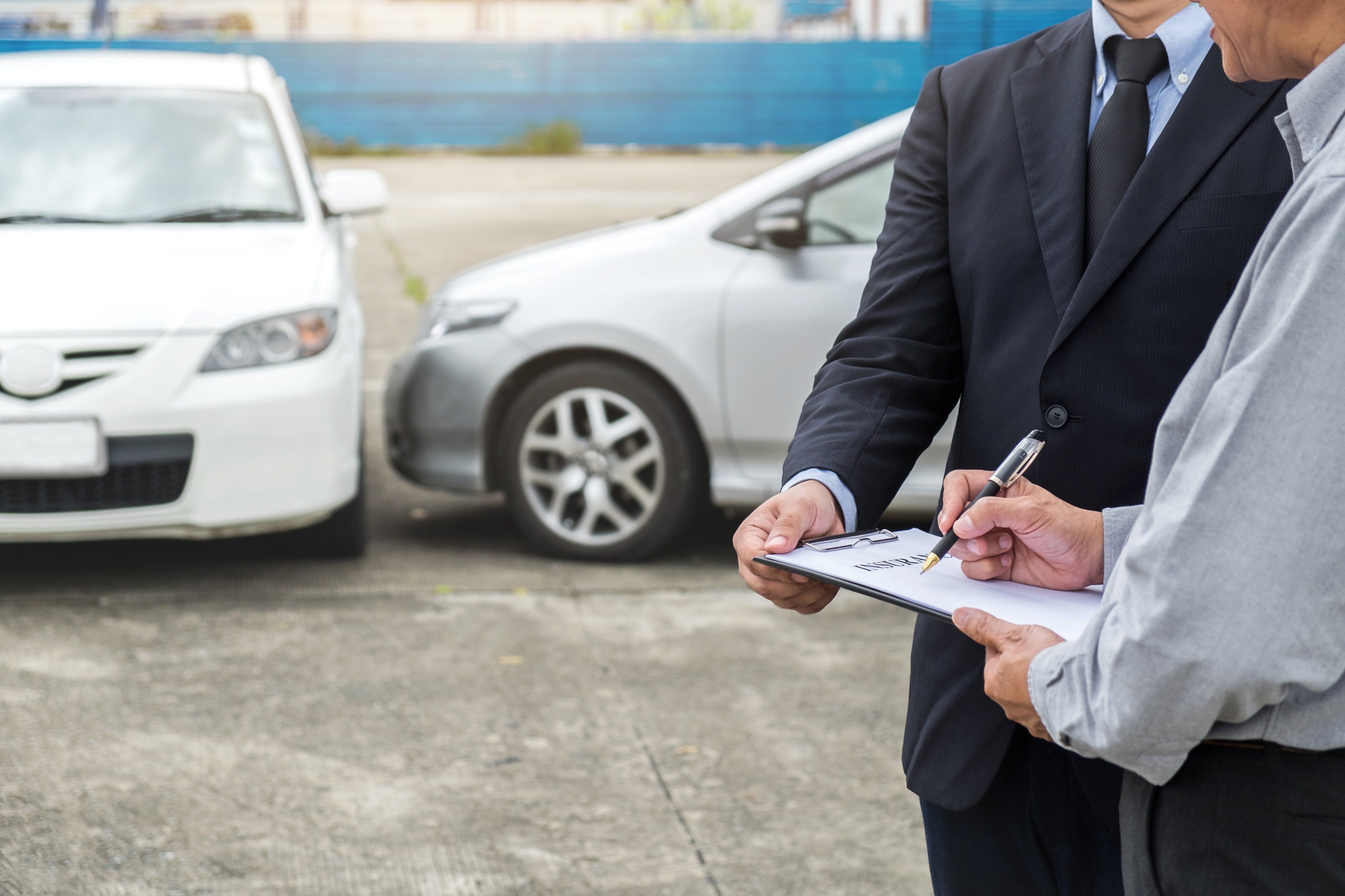 Insurance Agent examine Damaged Car and customer filing signature on Report Claim Form process after accident, Traffic Accident and insurance concept.