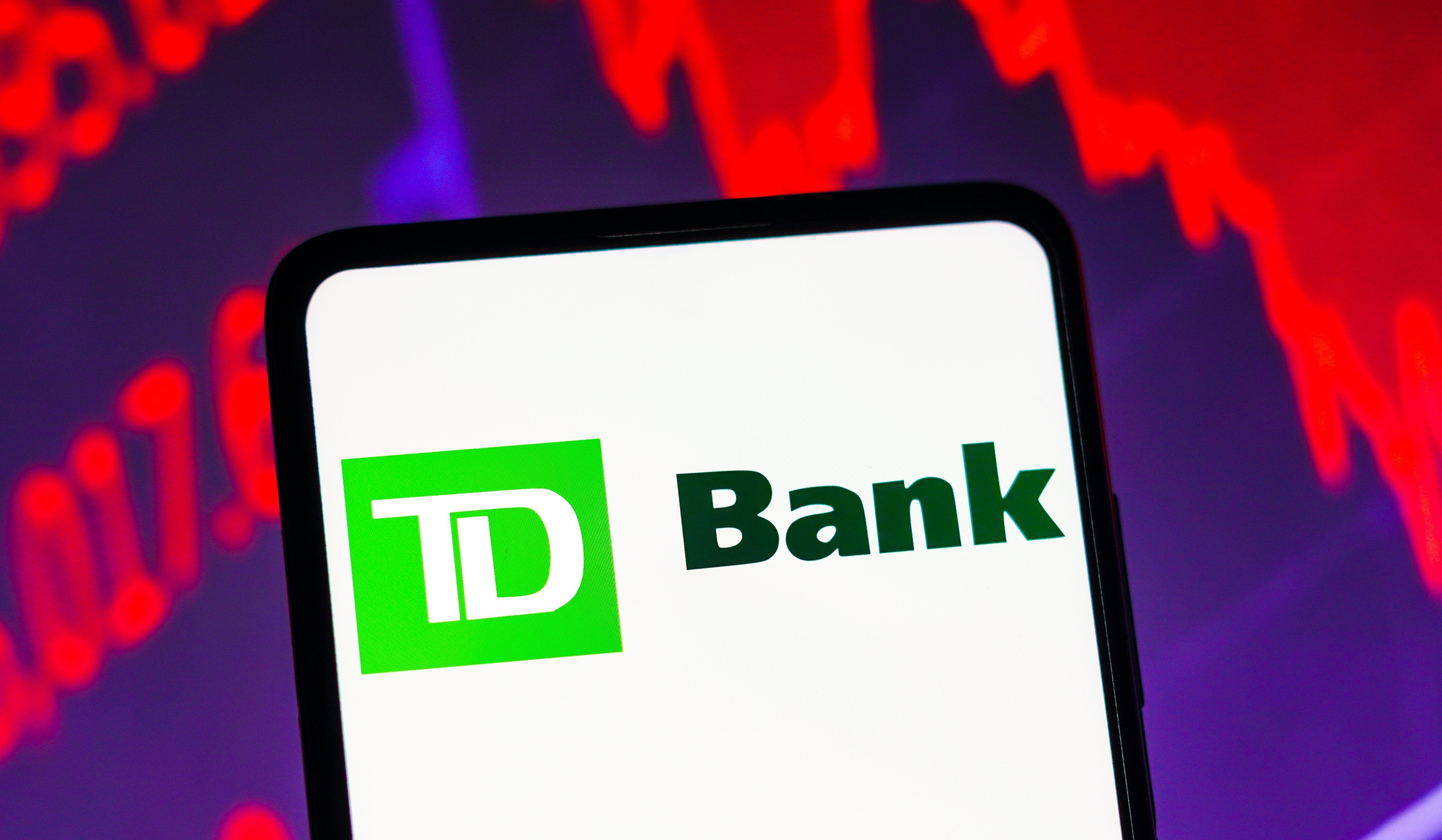 August 11, 2023, Brazil. In this photo illustration the TD Bank logo seen displayed on a smartphone screen, with graphic representation of the stock market in the background