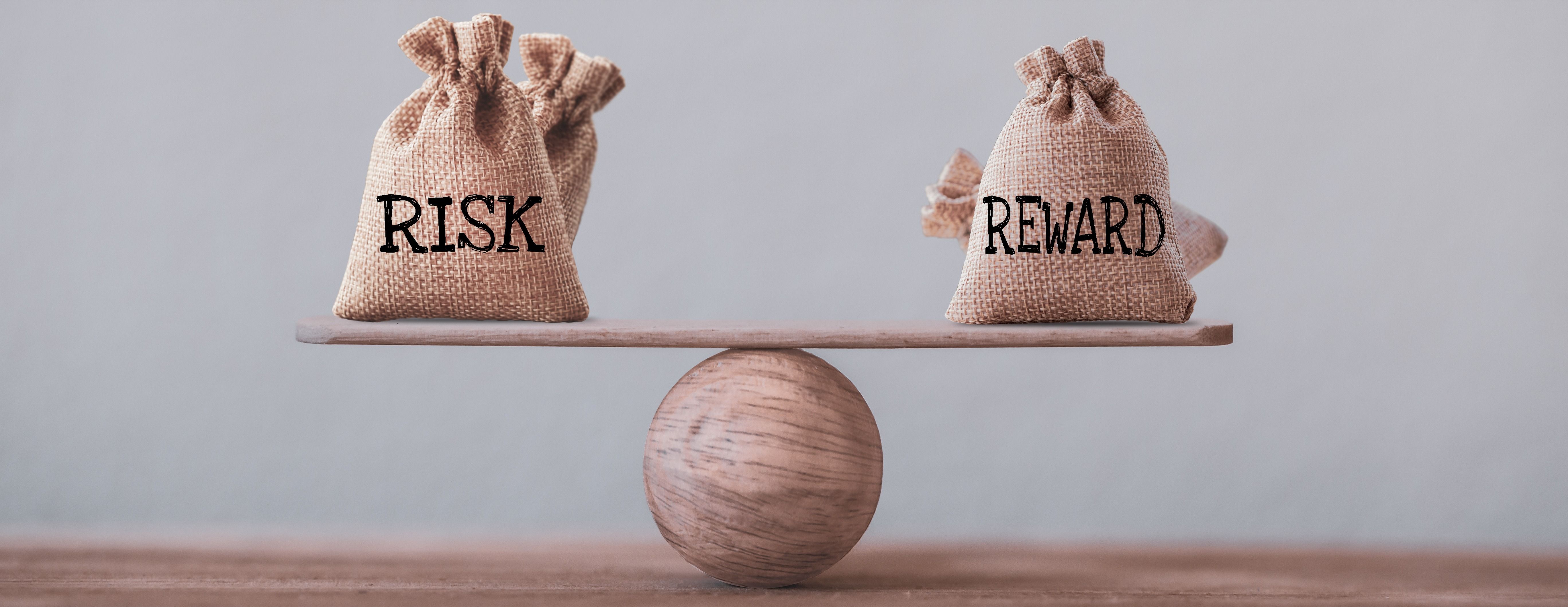 Risk and reward bags on a basic balance scale in equal position on wood table