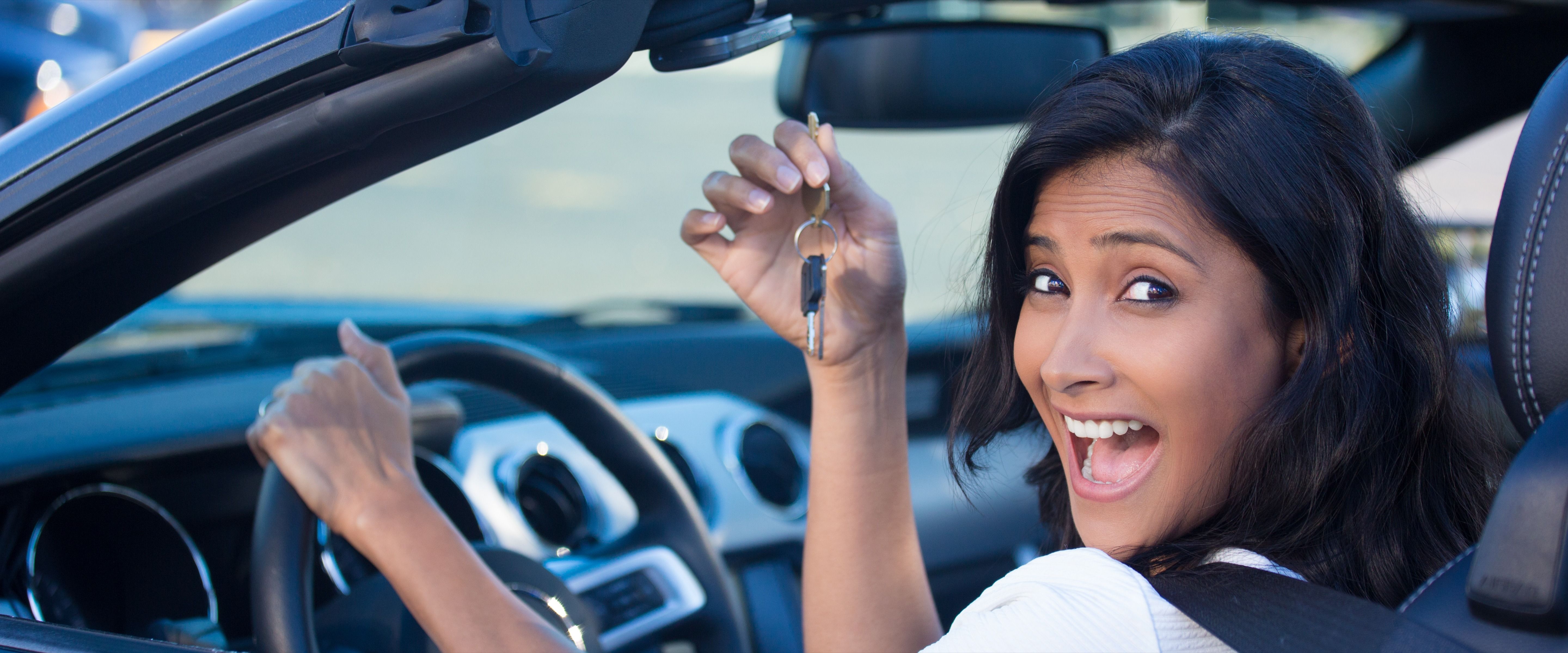 Woman holding up keys to her first new car.
