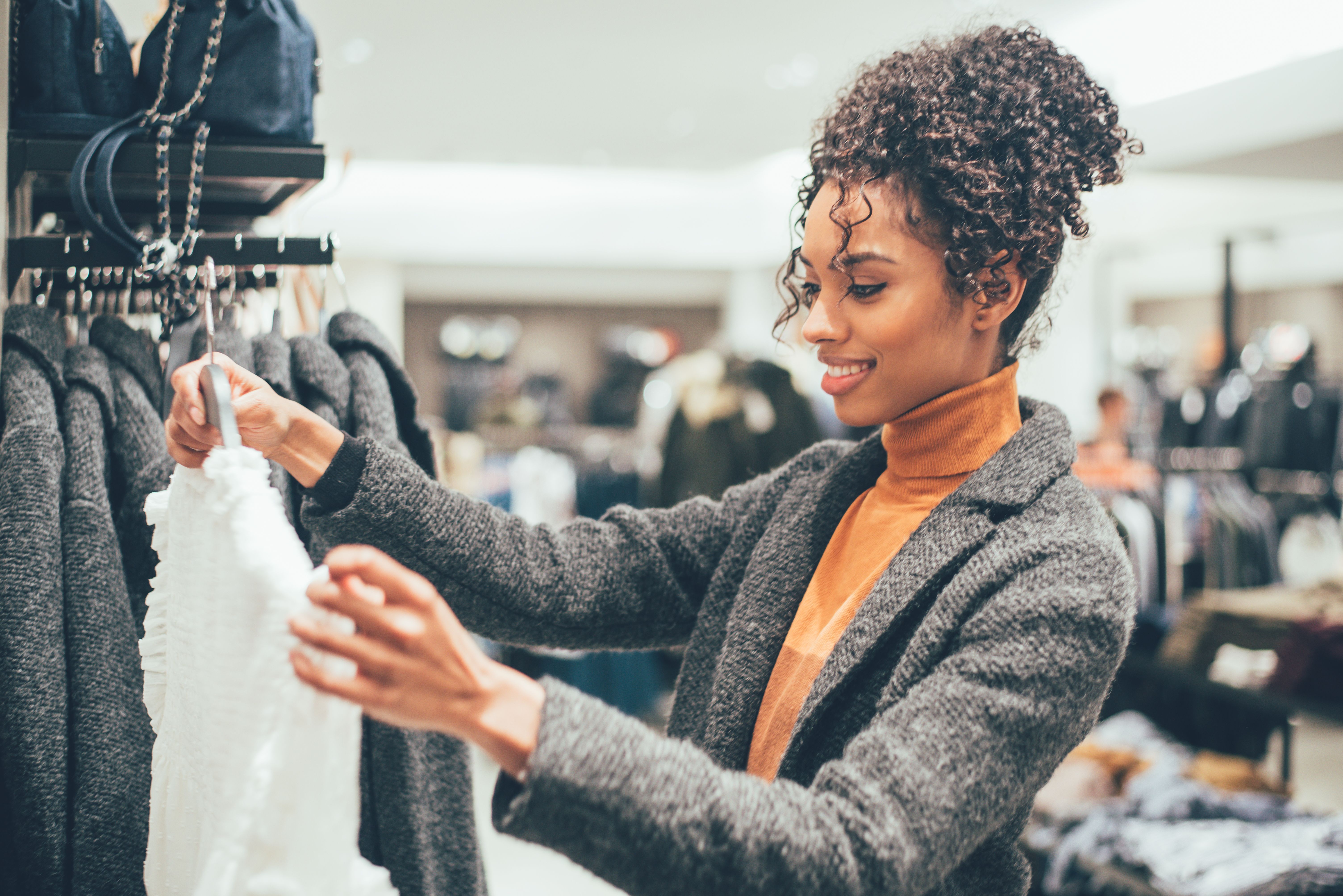 Clothing store worker helps client on black friday, showing new clearance  items at half price. Woman giving clothes to old shopper, bargain hunting  on big sales day. Handheld shot. 31722835 Stock Photo