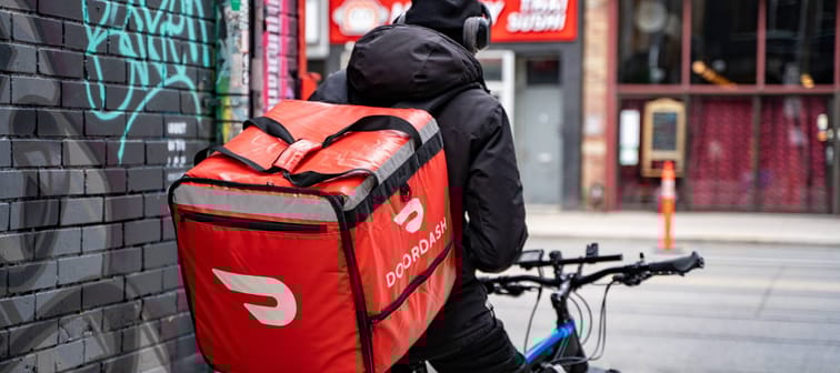 A DoorDash food delivery courier on an bicycle. Toronto, Canada - May 25, 2024