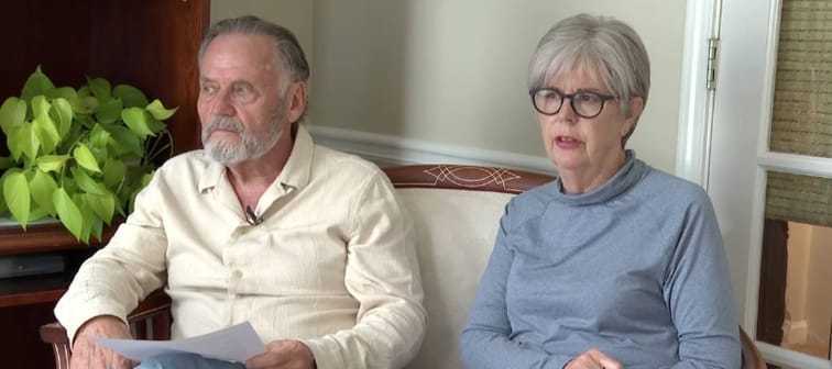 Man and woman sitting on a couch on camera.