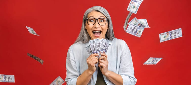 Older woman clutches at money as it falls around her