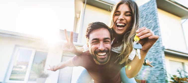 Happy couple holding up keys to house they just bought