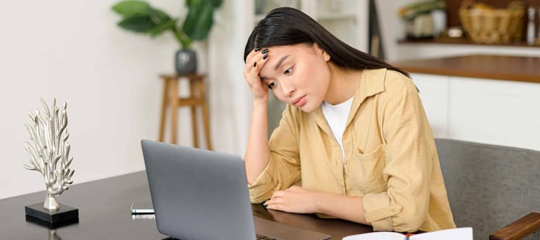 Stressed young Asian woman looking at her laptop