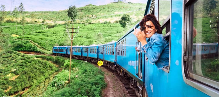 Woman traveler explores natural landscape via train, looking happy