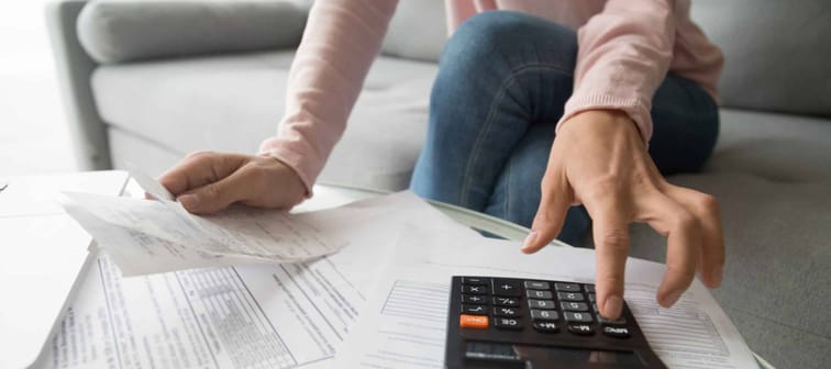 Woman renter holding paper bills using calculator for financial bills