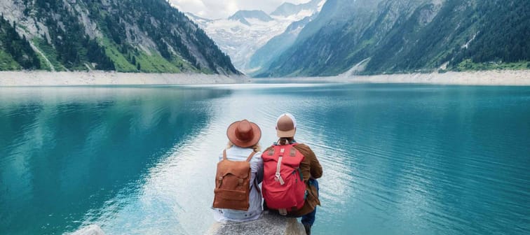 Travelers couple look at the mountain lake. Travel and active life concept with team. Adventure and travel in the mountains region in the Austria