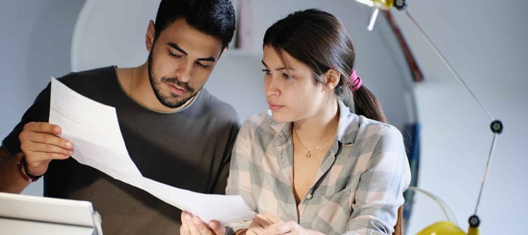 Young couple reviewing invoices and doing family business plan. Concept of money and economic problem for man and woman living together