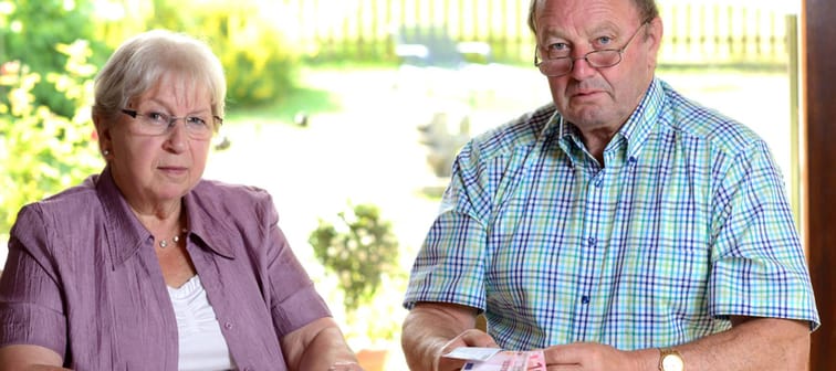 Older couple sit at a table reviewing money and finances