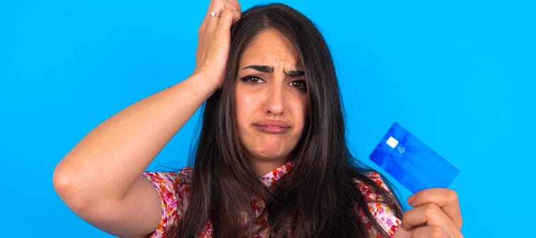 Unhappy young woman holds up a credit card