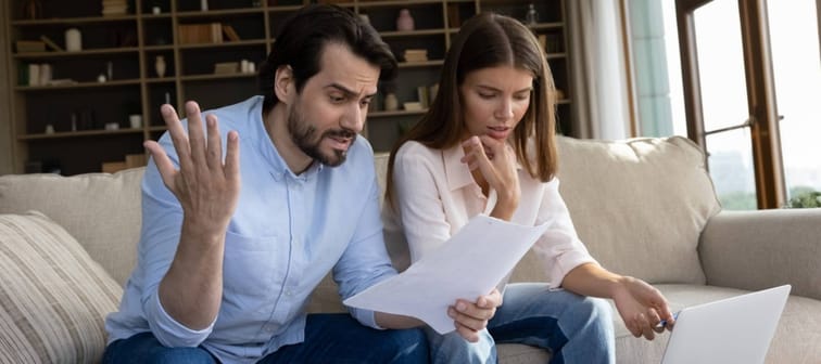 Unhappy couple reviewing their finances in their living room