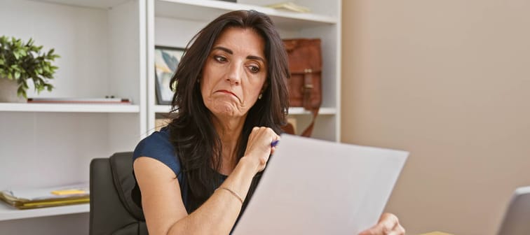 Unhappy middle-aged woman looking at paperwork and bills