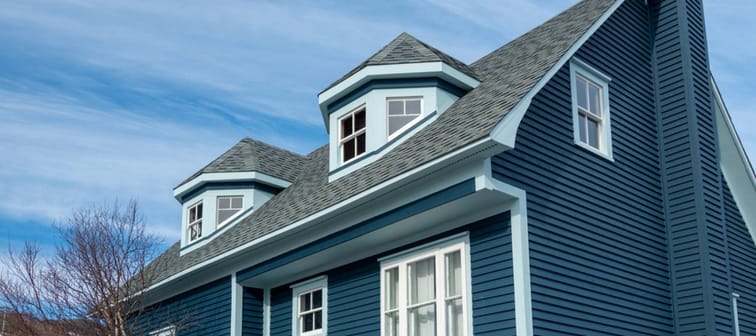 The exterior view of two polygonal dormers on a modern blue rooftop of a wooden house