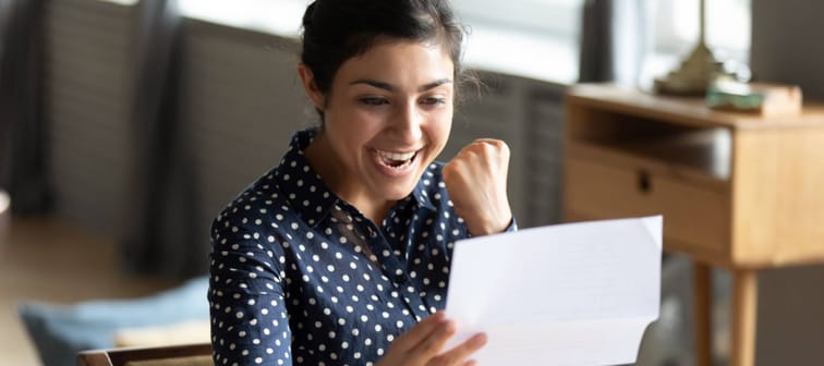 Young woman excited to be getting a raise, sitting in front of laptop