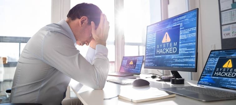 Distressed man sitting in front of hacked computer