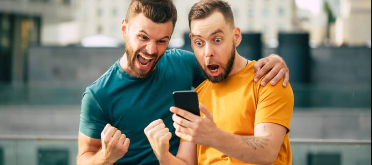 Two friends excited while looking at phone