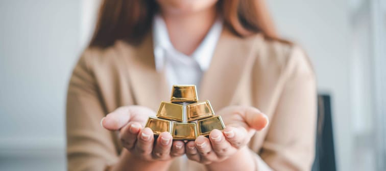 Business woman holding gold bar stack in her hand