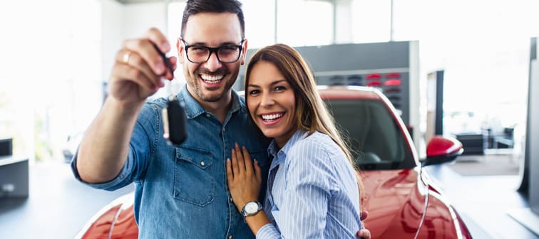 Young couple happily holding keys to new car