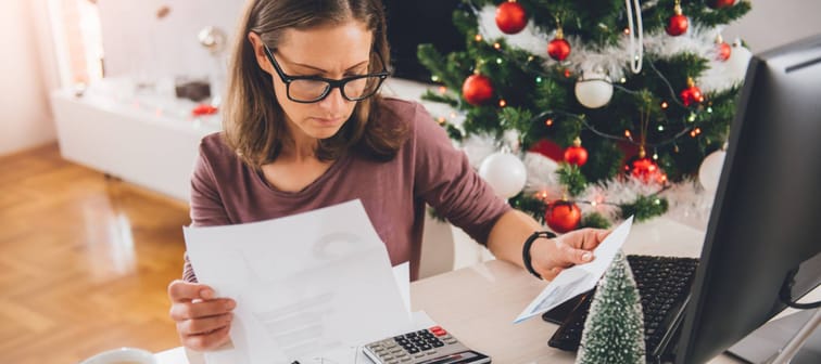 Woman deciphering paperwork surrounded by holiday decorations