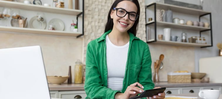 Young woman calculating at kitchen counter