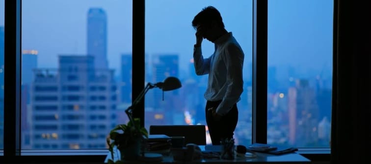 Asian business man being frustrated standing in office hopelessly