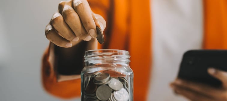 A saver adding money into a money jar