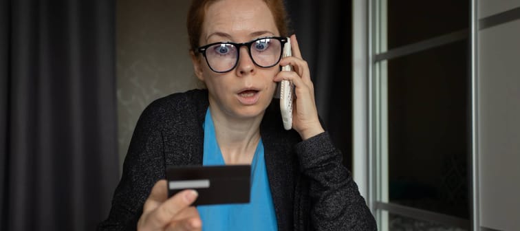 Woman with smartphone talking to phone scammers, hacker impersonating banking official, money transfer initiated.