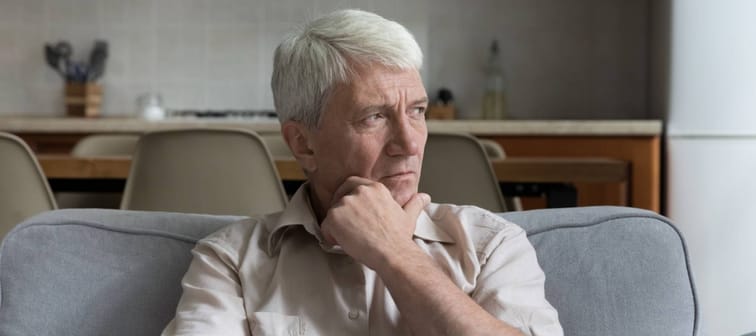 Pensive stressed mature 70s man holding laptop computer