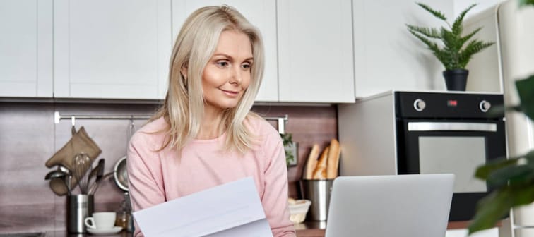 Middle aged mature woman holding paper bill or letter