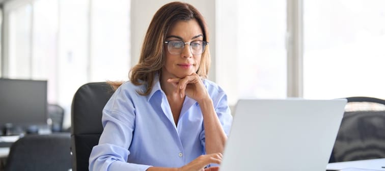 Busy elegant middle aged business woman using laptop working in corporate office