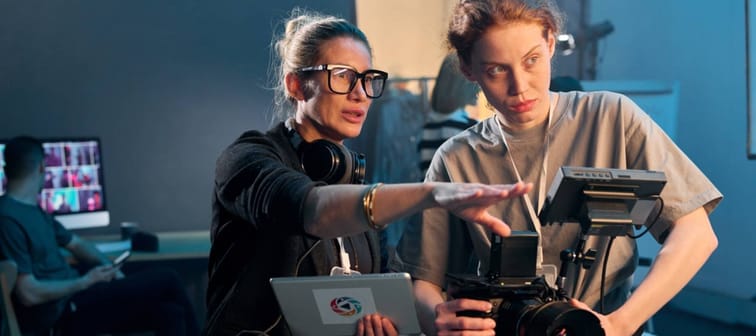 Waist up portrait of female director giving instructions working in video production and operating cameras