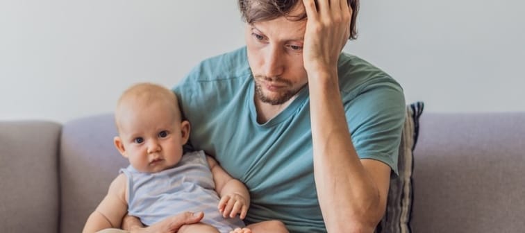 A photo of a father holding a baby looking distressed.