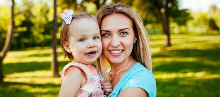 Happy mom and daughter smiling outside at a park.