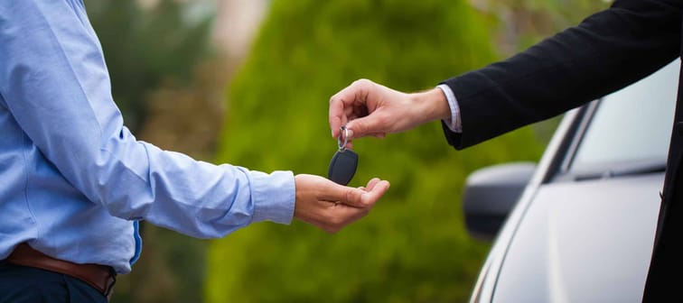 Man gives a car key to the other man
