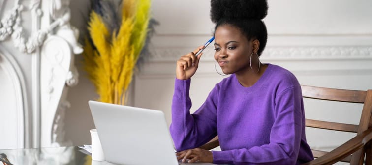 Black millennial woman employee working on laptop and feeling visibly annoyed.