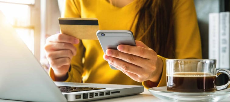 businesswoman hand using smart phone, tablet payments and holding credit card online shopping, omni channel, digital tablet docking keyboard computer at office in sun light