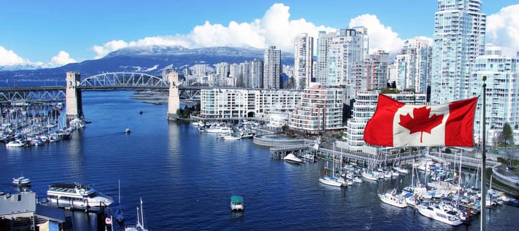 Canadian flag in front of view of False Creek and the Burrard street bridge in Vancouver, Canada.