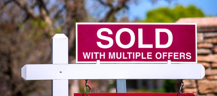 SOLD With Multiple Offers real estate sign near purchased house indicates red hot seller's market in the desired residential neighborhood.