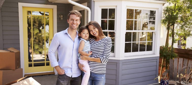 Portrait Of Excited Family Standing Outside New Home