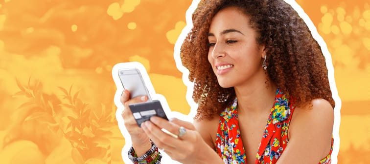 Black woman in colourful top using credit card and mobile banking.