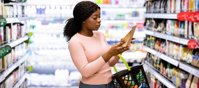 Focused female consumer shopping for groceries, selecting food, reading labels at modern mall