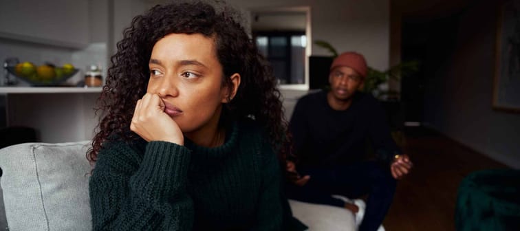 Multi-cultural female ignoring black boyfriend while fighting on the sofa in modern apartment