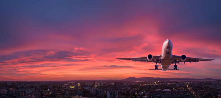 Airplane is flying in colorful sky over the city at night.