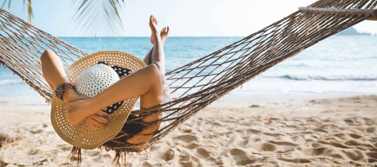 Summer travel vacation concept, Happy traveler asian woman with white bikini relax in hammock on beach in Koh mak, Thailand