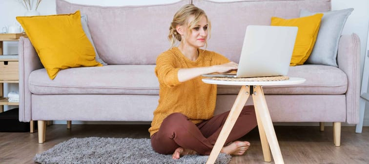 Attractive woman sitting on floor and sofa using laptop
