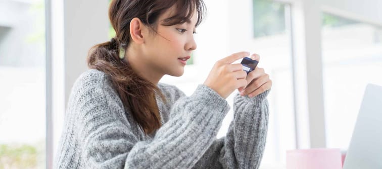 Young woman looking for number at back of credit card for online shopping