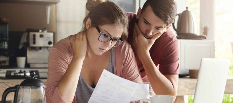 Caucasian couple looking worried about their loans. The couple is looking at documents.